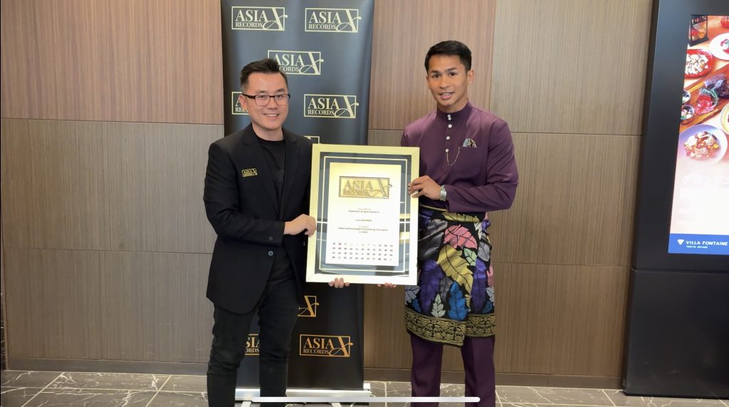 The official adjudicators from The Asia Records presenting Superbon the award, standing side by side during an award presentation, holding a framed Asia Records certificate, with an Asia Records backdrop behind them.