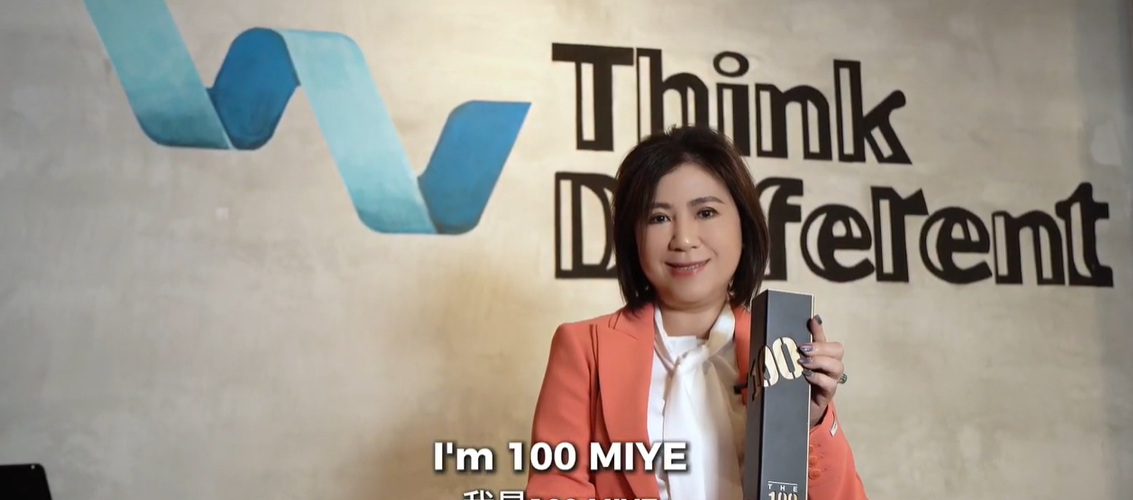 Ellen Lum in a coral blazer holding a “Top 100 Most Influential Young Entrepreneurs” award.