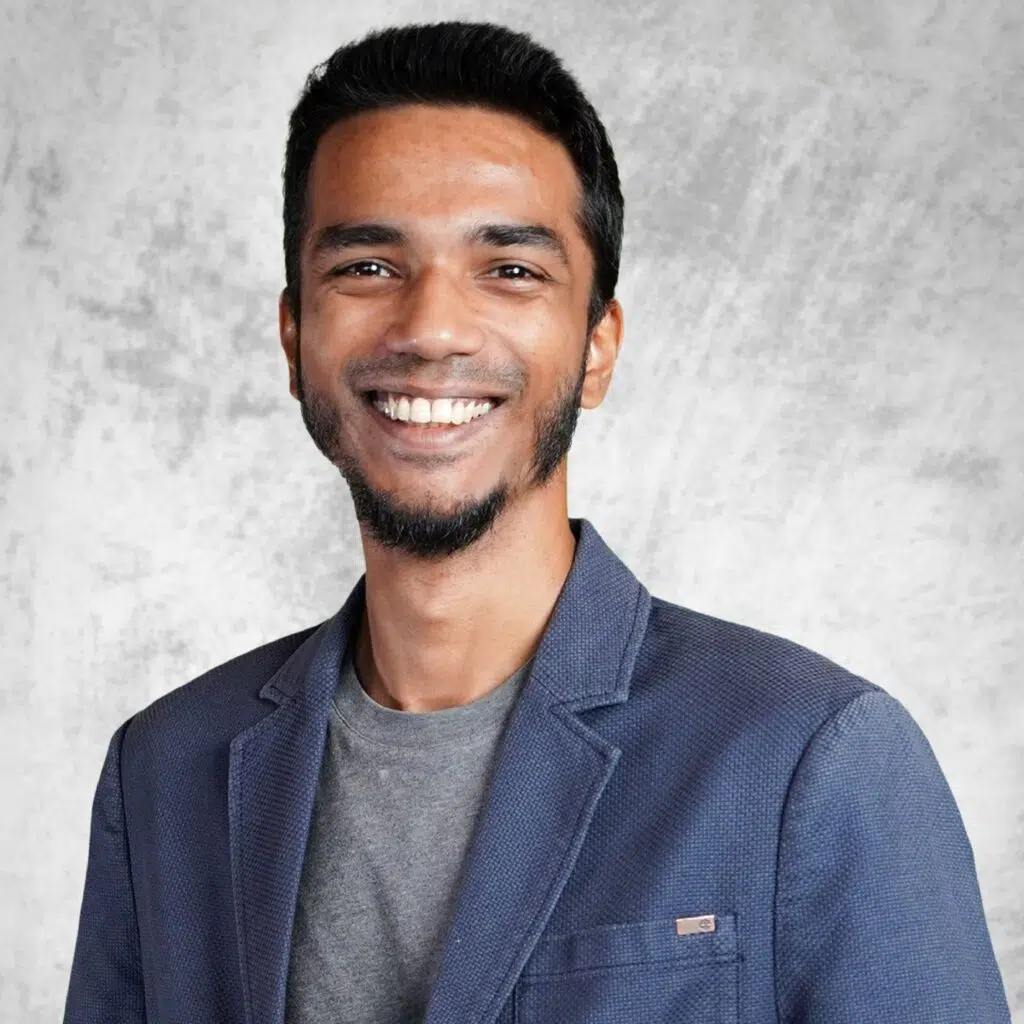 Vinesh Sinha in a blue blazer against a textured light grey studio