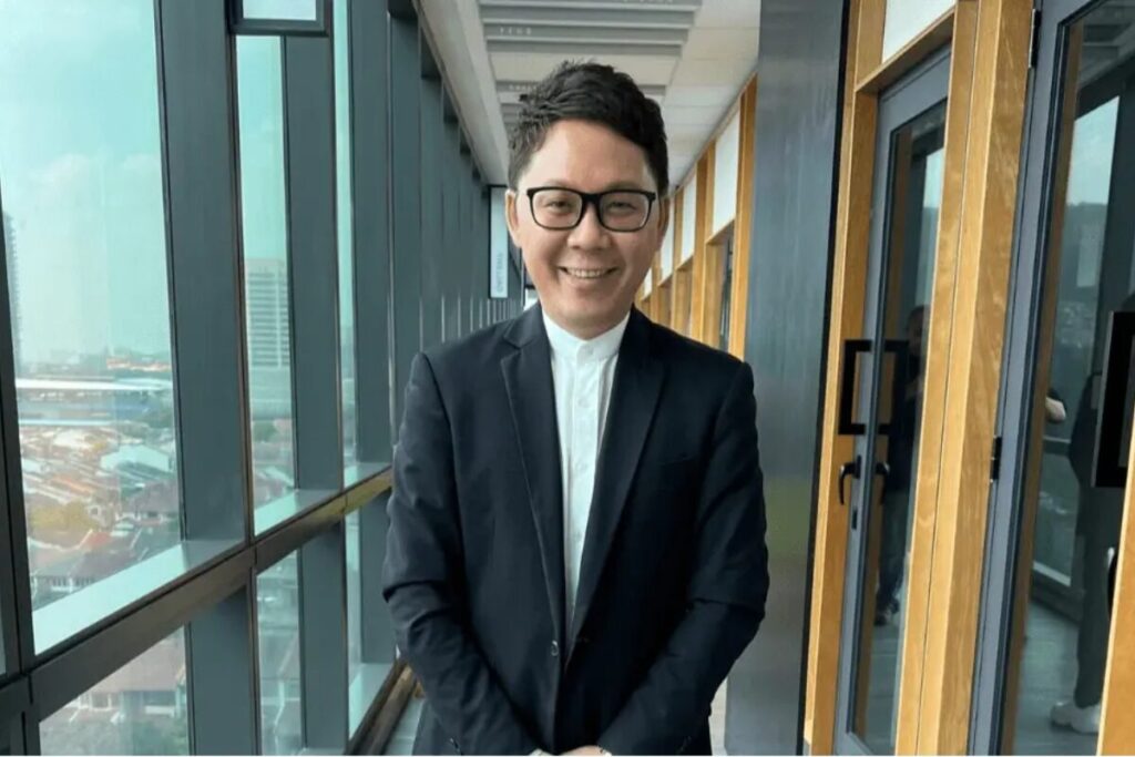 Dato’ Calvin Chan in a dark suit standing in a modern office corridor