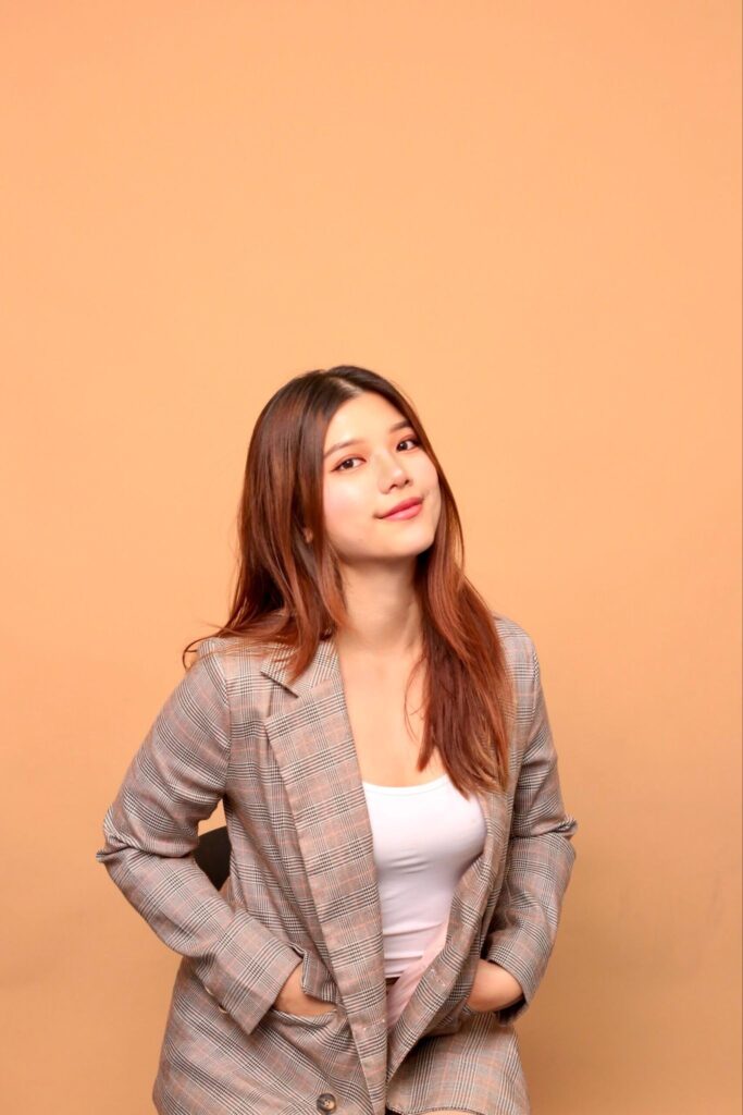 Ivor Lim in a checked blazer against a warm neutral studio background.