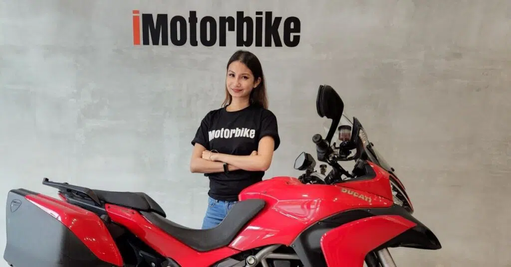 Sharmeen Looi standing beside a red motorcycle in a modern showroom