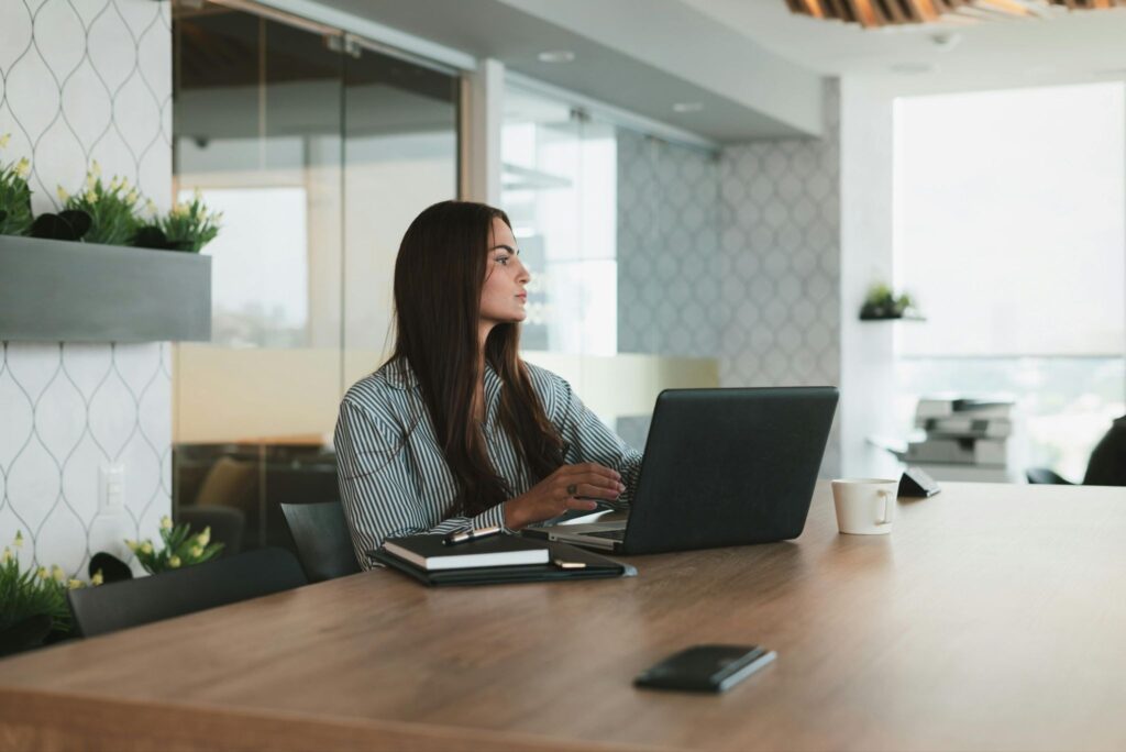 Female entrepreneur working on a laptop at a meeting table in a modern office workspace
