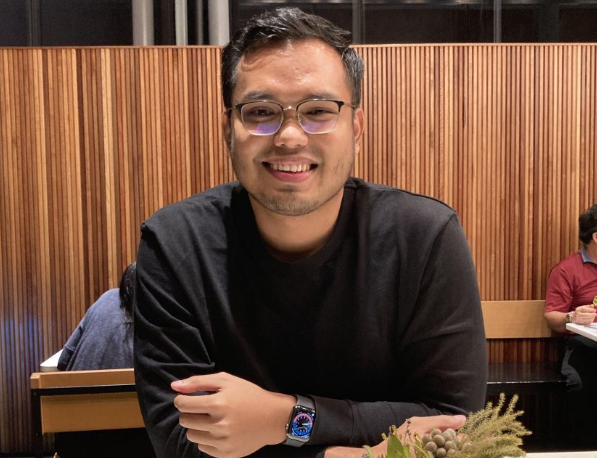 Khairul Aming in glasses and a black sweatshirt sitting at a restaurant table