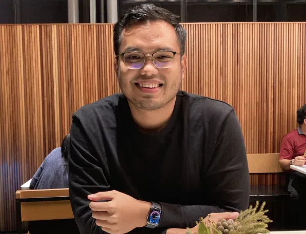 Khairul Aming in glasses and a black sweatshirt sitting at a restaurant table