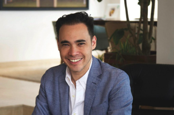 patrick grove,  co-founder and Group CEO of Catcha Group, in a blue suit and white shirt is sitting at a desk, appearing concentrated on his work.