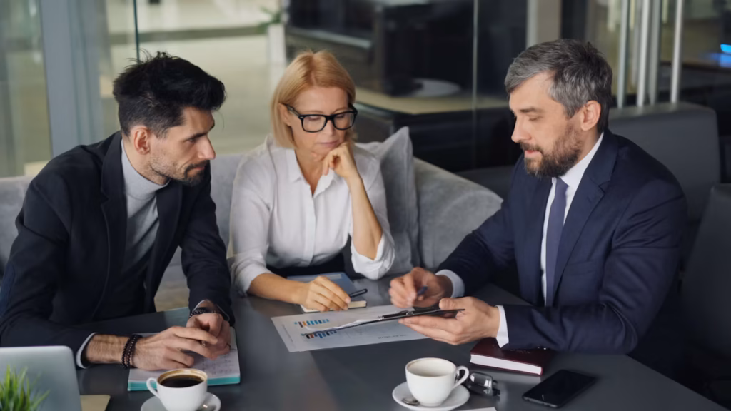 Three business professionals reviewing a financial report during a consultation meeting in a modern office.