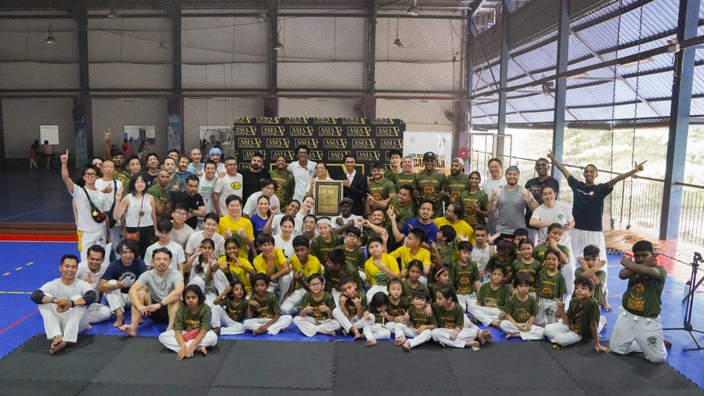 Capoeira Cordão de Ouro Malaysia participants posing for a group photo with the Asia Record certificate at an indoor sports venue